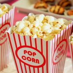Close-up of gourmet popcorn in classic red and white striped boxes, perfect cinema snack.